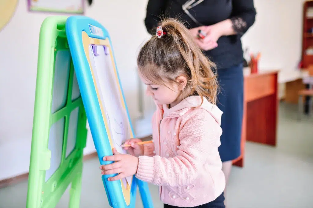 Petite fille écrivant sur un tableau blanc dans une école.