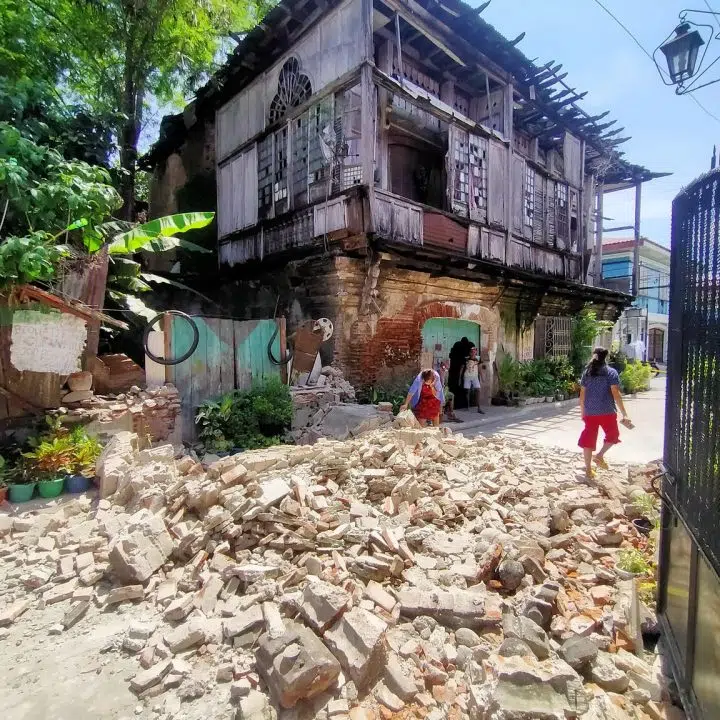 Le 27 juillet 2022, des habitants passent devant les débris d'une vieille maison à Vigan City, dans la province d'Ilocos Sur, au nord de Manille, après le tremblement de terre de magnitude 7,0 qui a frappé le nord des Philippines. © UNICEF/UN0677914/Arduengo/AFP