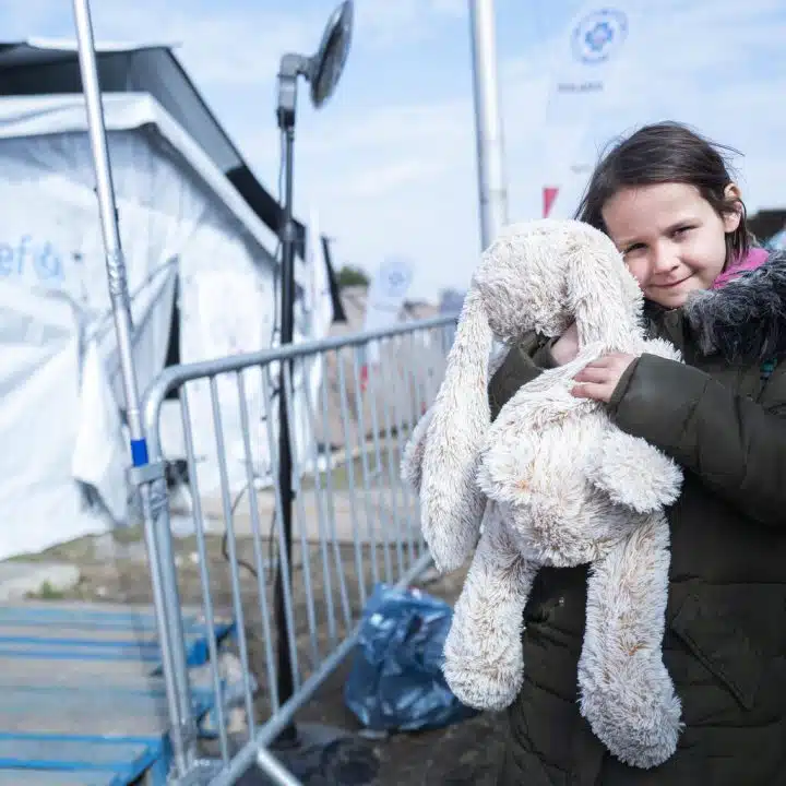 Le 25 mars 2022, Nastja, 7 ans, prends dans ses bras son jouet préféré, un gros lapin en peluche, près de la tente de l'UNICEF à la frontière de Medyka (Pologne) après avoir fui le conflit en Ukraine. © UNICEF/UN0623746/Korta