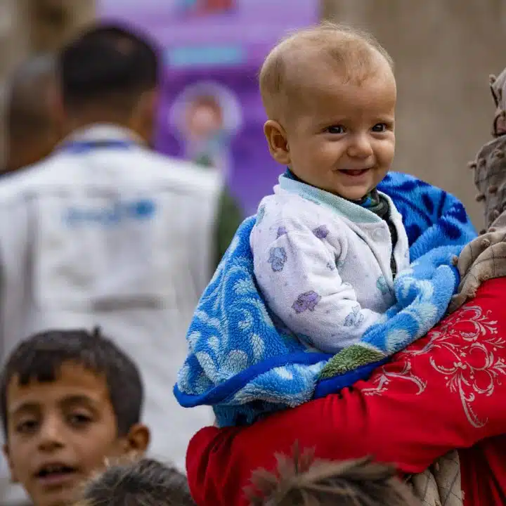 Rawda tient Ariam, 6 mois, en attendant son tour pour vacciner son fils par une équipe mobile du ministère de la Santé dans le quartier de Ghwairan, ville de Hasakeh, nord-est de la Syrie, le 26 octobre 2022. © UNICEF/UN0757751/Souleiman