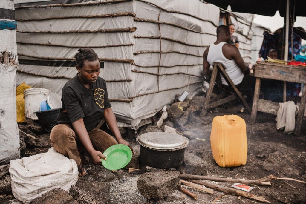 Anuarite, 18 ans, cuisine en utilisant de l'eau provenant d'une des bornes-fontaines installées par l'UNICEF dans le camp de déplacés de Bulengo, près de Goma, dans la province du Nord-Kivu, en République démocratique du Congo, le 28 février 2024.© UNICEF/UNI538362/Benekire