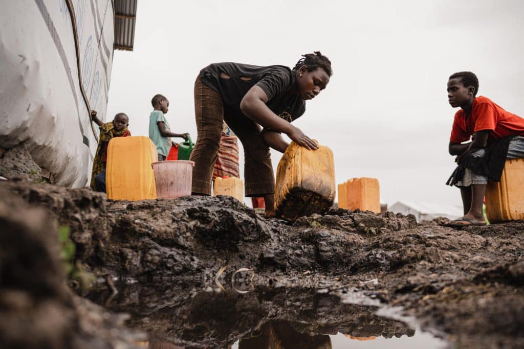 Le 28 février 2024, Anuarite, 18 ans, lave son bidon avant de prélever de l'eau à l'une des bornes-fontaines installées par l'UNICEF dans le camp de déplacés de Bulengo, près de Goma, dans la province du Nord-Kivu, en République démocratique du Congo.© UNICEF/UNI538367/Benekire