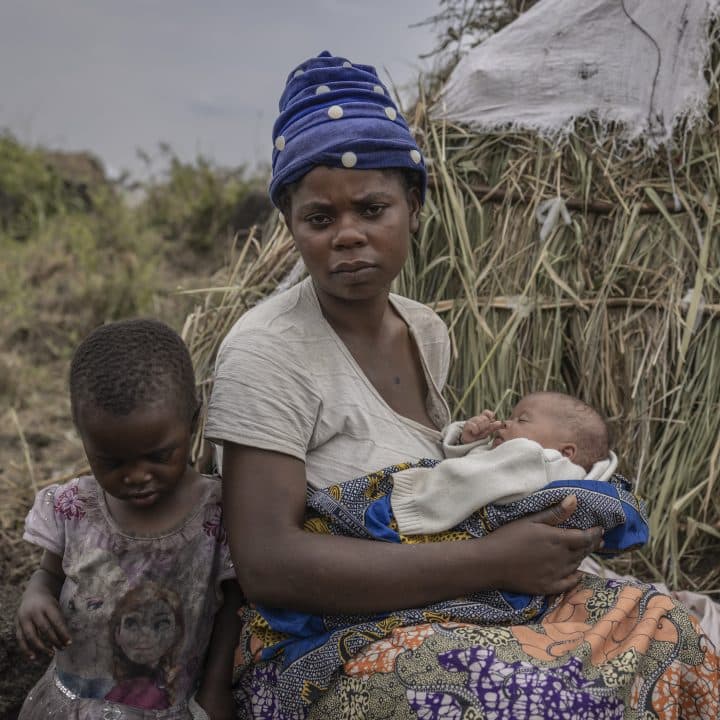 Fazili Muhunde tient son bébé Plamedi devant son abri au camp de Bulongo pour personnes déplacées dans la province du Nord-Kivu, République Démocratique Congo, le 8 février 2023.