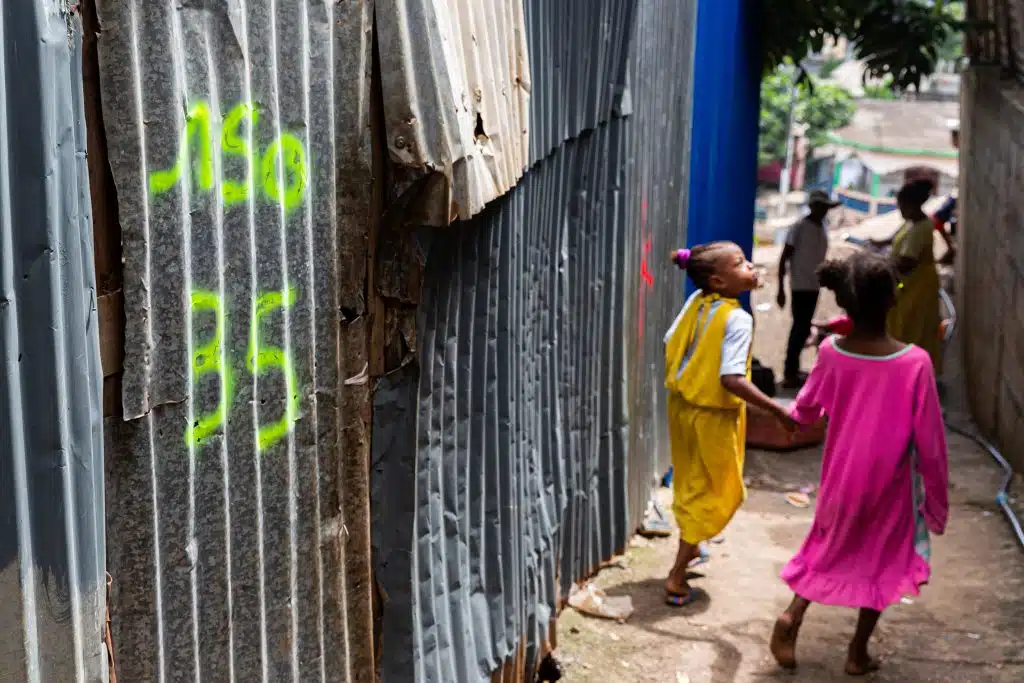 Mayotte, le 24 avril 2023 Des enfants passent devant une habitation dans un bidonville à Majicavo, une commune faisant de la ville de Koungou à Mayotte. (Photo by Morgan Fache / AFP)