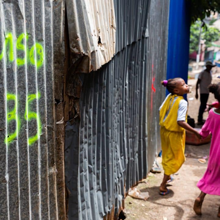 Mayotte, le 24 avril 2023 Des enfants passent devant une habitation dans un bidonville à Majicavo, une commune faisant de la ville de Koungou à Mayotte. (Photo by Morgan Fache / AFP)