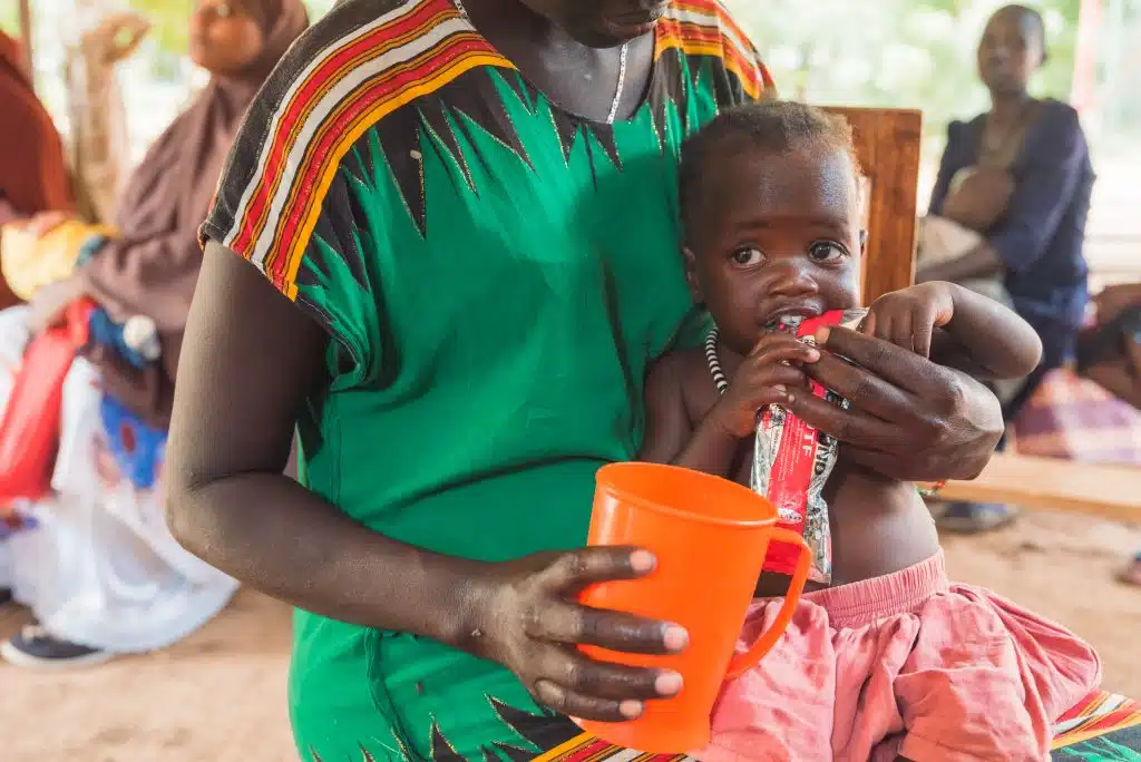 Dans le camp de réfugiés de Kakuma, au Kenya Sabina Naboi, mère d'Analia Wally, donne à sa fille des aliments thérapeutiques. Au Kenya, Six saisons de sécheresse sévère, accélérée par le changement climatique, ont eu un impact négatif sur l'état nutritionnel des habitants du comté de Turkana. © UNICEF/UNI431383/Kidero