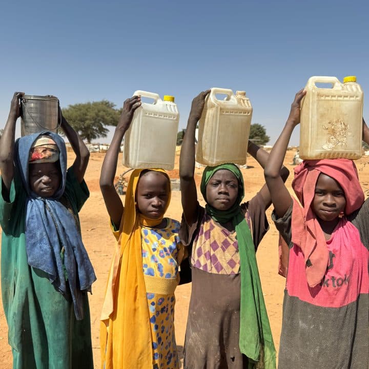 Le 3 février 2024, des enfants transportent des récipients d'eau après les avoir remplis dans un puits de l'UNICEF à l'intérieur du camp de réfugiés d'Adré, au Tchad. Près de la moitié des réfugiés soudanais arrivant au Tchad ont traversé la frontière par Adré. Ils ont établi un campement informel en attendant d'être relogés dans des camps plus éloignés de la frontière. À un moment donné, Adré a accueilli plus de 200 000 réfugiés, soit plus que la population de la ville. Aujourd'hui, le campement se vide peu à peu, mais des dizaines de milliers de personnes attendent toujours, dans des conditions extrêmement difficiles. © UNICEF/UNI514949/Le Du