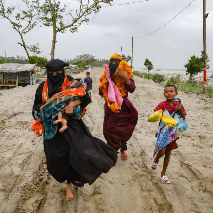 Des habitants du village de Panjupara se dirigent vers les abris avec leurs enfants et leurs objets de valeur pendant les pluies à Kuakata, avant l'arrivée du cyclone Remal au Bangladesh, le 26 mai 2024. © UNICEF/UNI581132