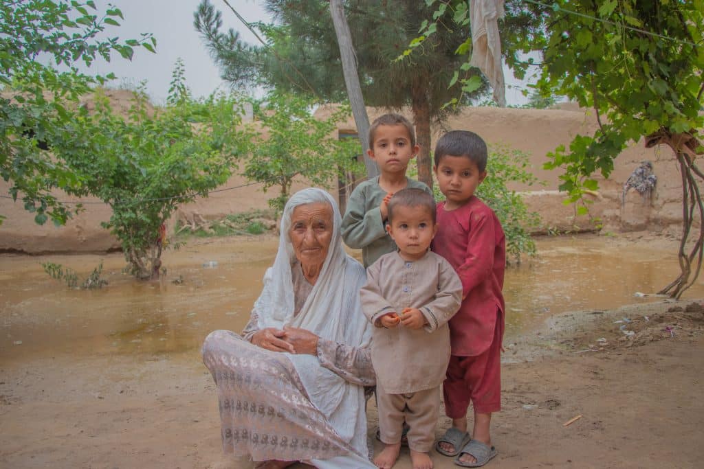 Le 16 mai 2024, Bigom, et ses trois petits-fils après les inondations soudaines dans son village, en Afghanistan. © UNICEF/UNI577384/Khayyam