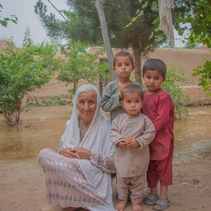 Le 16 mai 2024, Bigom, et ses trois petits-fils après les inondations soudaines dans son village, en Afghanistan. © UNICEF/UNI577384/Khayyam