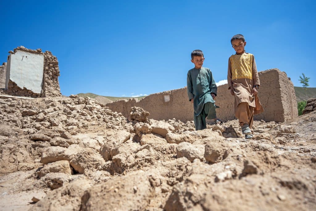 Le 28 mai 2024, Farzan, 9 ans, marche dans les ruines de sa maison dans le district de Chaghcharan, dans la province de Ghor, dans l'ouest de l'Afghanistan. Farzan, qui porte les vêtements de son cousin, a tout perdu lorsque de fortes pluies et des crues soudaines ont emporté sa maison le 19 mai. © UNICEF/UNI584909/Naftalin