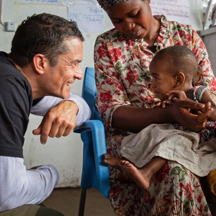 1er juin 2024, Orlando Bloom, ambassadeur de l'UNICEF, salue un enfant lors d'une visite au site de Bushagara pour les personnes déplacées à l'intérieur du pays. © UNICEF/UNI585410/Tremeau