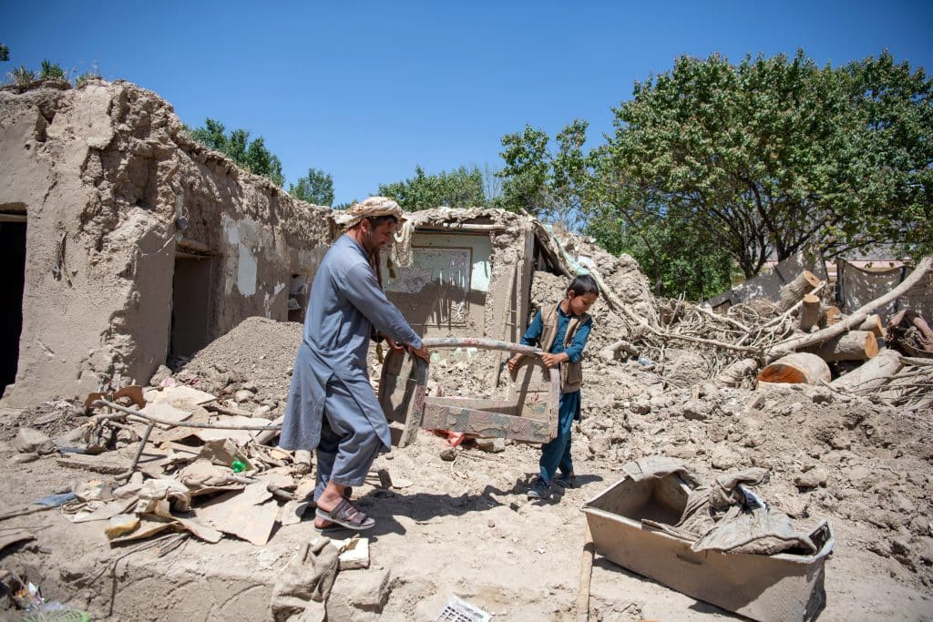Le 3 juin 2024, Hassan et son père se tiennent devant leur maison détruite par les inondations qui ont touché leur village dans la province de Baghlan, au nord de l'Afghanistan.© UNICEF/UNI586031/Musadiq