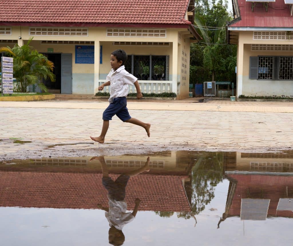 Au Cambodge, un élève joue dans la cour de récréation de son école inondée par les eaux de pluie en septembre 2022. © UNICEF/UN0708998/Meas