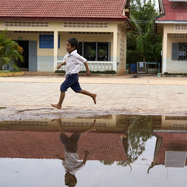 Au Cambodge, un élève joue dans la cour de récréation de son école inondée par les eaux de pluie en septembre 2022. © UNICEF/UN0708998/Meas