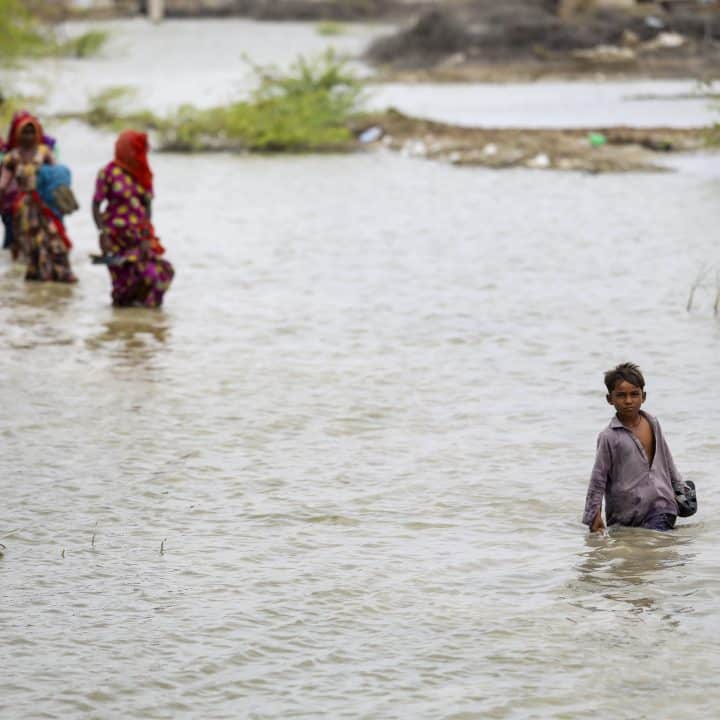 Le 24 septembre 2022, des enfants et des femmes marchent dans le village inondé de Sonpur, au Pakistan. © UNICEF/UN0750104/Zaidi
