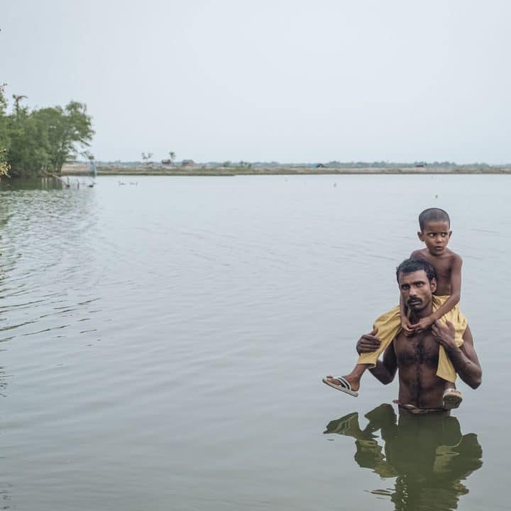 Sirajul traverse une zone inondée avec sa fille de 6 ans, sur ses épaules. Les inondations dévastatrices qui ont frappé le Bangladesh en mai 2019, ont emporté leur maison. © UNICEF/UNI424978/Sokhin