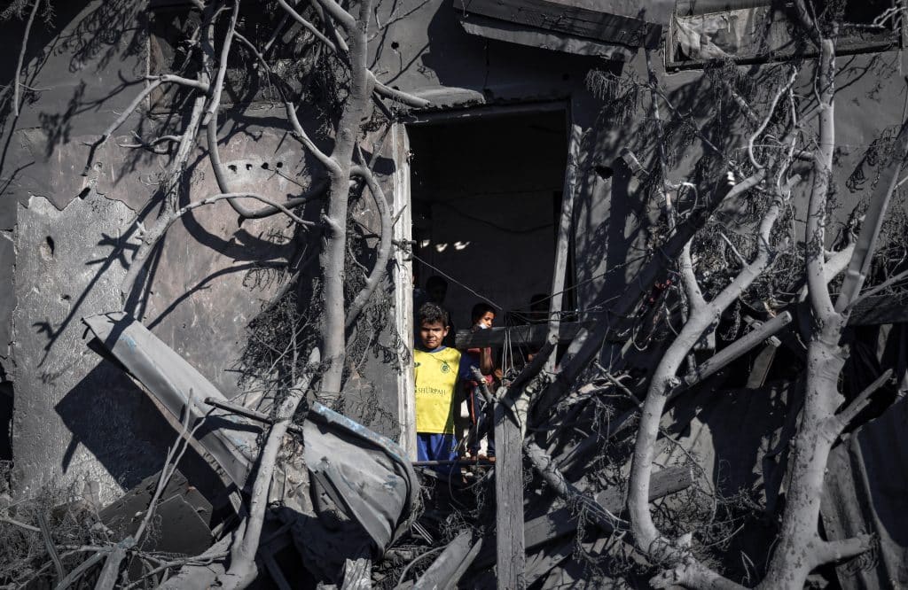 Un garçon regarde par la porte de sa maison les ruines après le bombardement de la ville de Rafah, dans la bande de Gaza. © UNICEF/UNI485685/El Baba