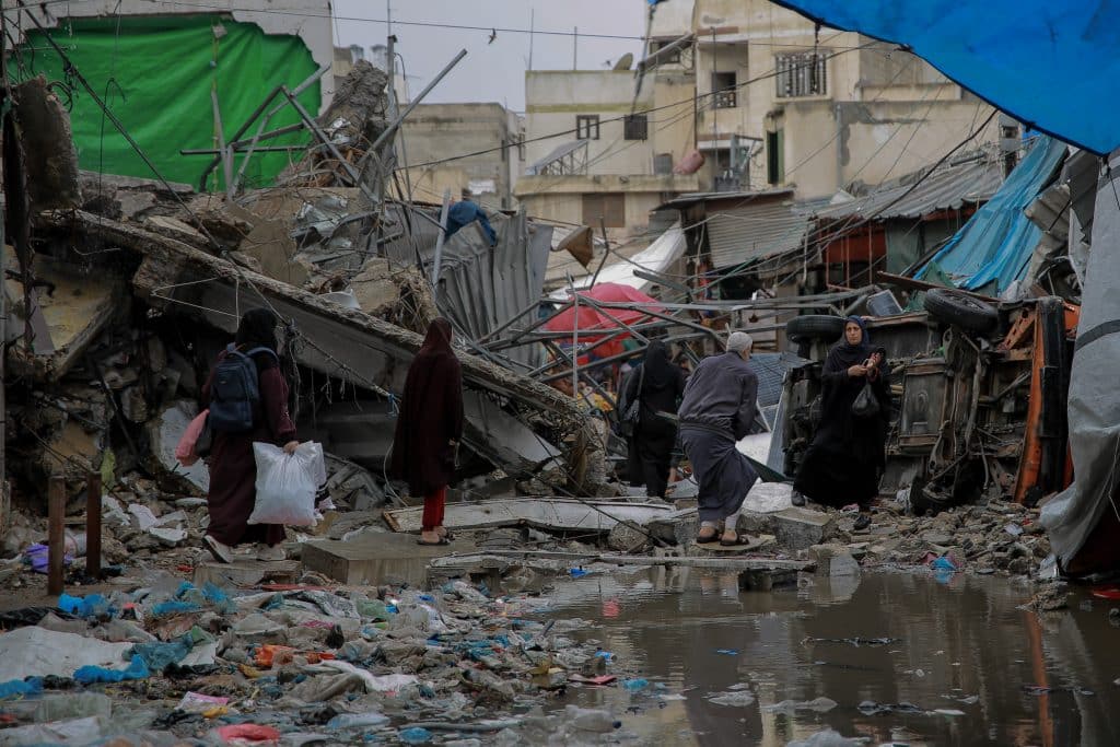 Des personnes traversent la route devant un magasin détruit par les bombardements dans le marché historique d'Azzawieh, dans la ville de Gaza. © UNICEF/UNI488758/Al-Qattaa