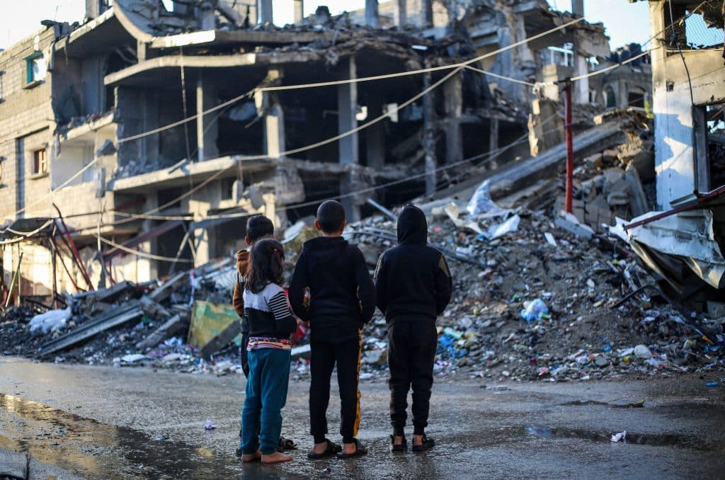 Des enfants se tiennent devant une maison démolie par un bombardement dans la ville de Rafah, au sud de la bande de Gaza. © UNICEF/UNI521727/El Baba