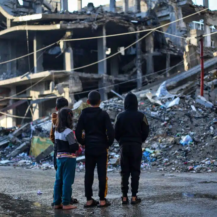 Des enfants se tiennent devant une maison démolie par un bombardement dans la ville de Rafah, au sud de la bande de Gaza. © UNICEF/UNI521727/El Baba