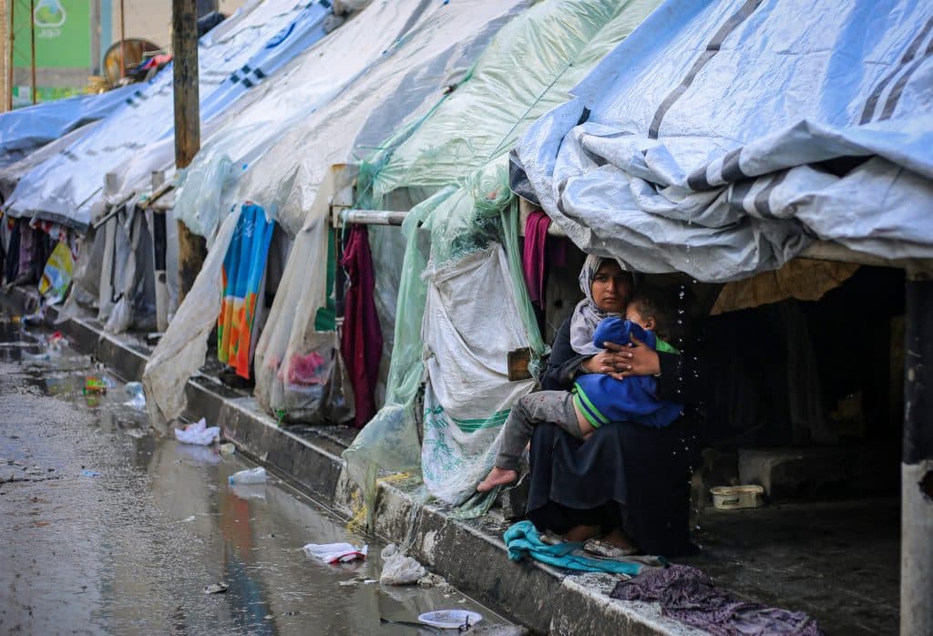 À l'intérieur d'une tente dans la ville de Rafah, cette mère essaye de garder son enfant au chaud. © UNICEF/UNI521734/El Baba