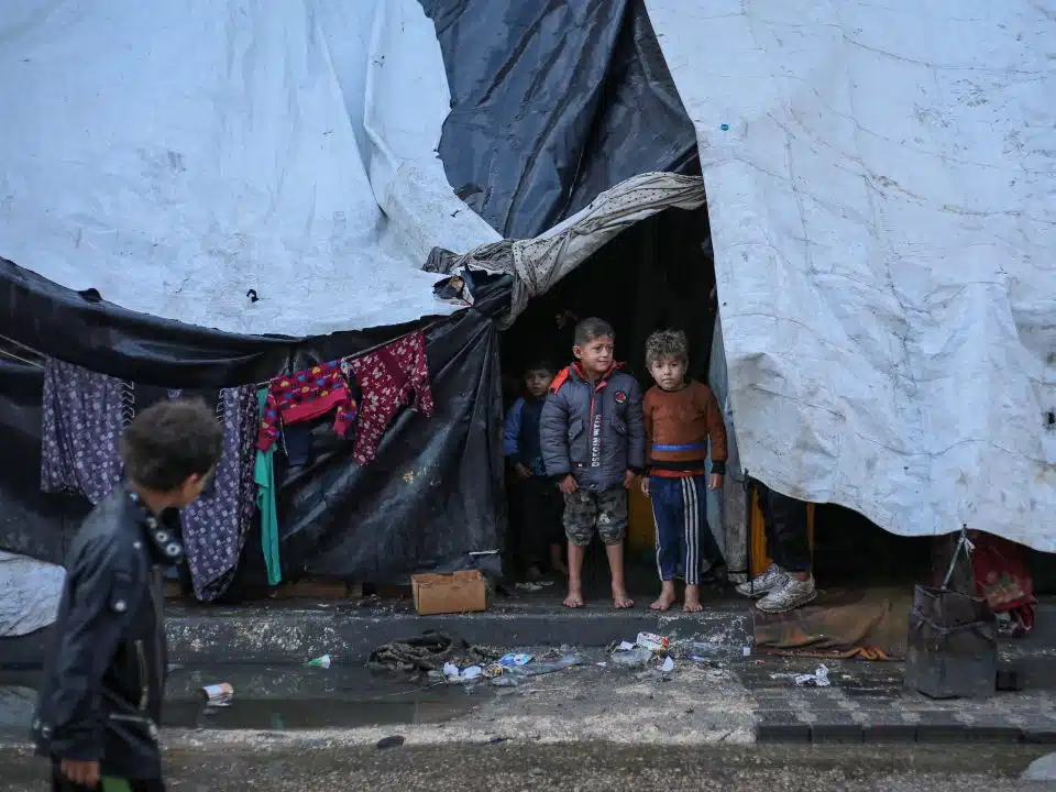 Deux enfants se tiennent pieds nus devant une tente qui leur sert de refuge dans la ville de Rafah, au sud de la bande de Gaza. © UNICEF/UNI521798/El Baba