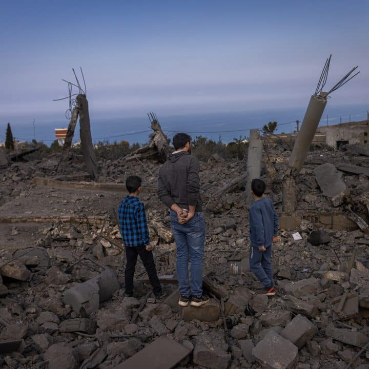 Un père et ses fils se tiennent au centre d'une zone habitable détruite, à Majdal Zoun, au Sud du Liban. ©UNICEF/UNI561769/Ibarra Sánchez