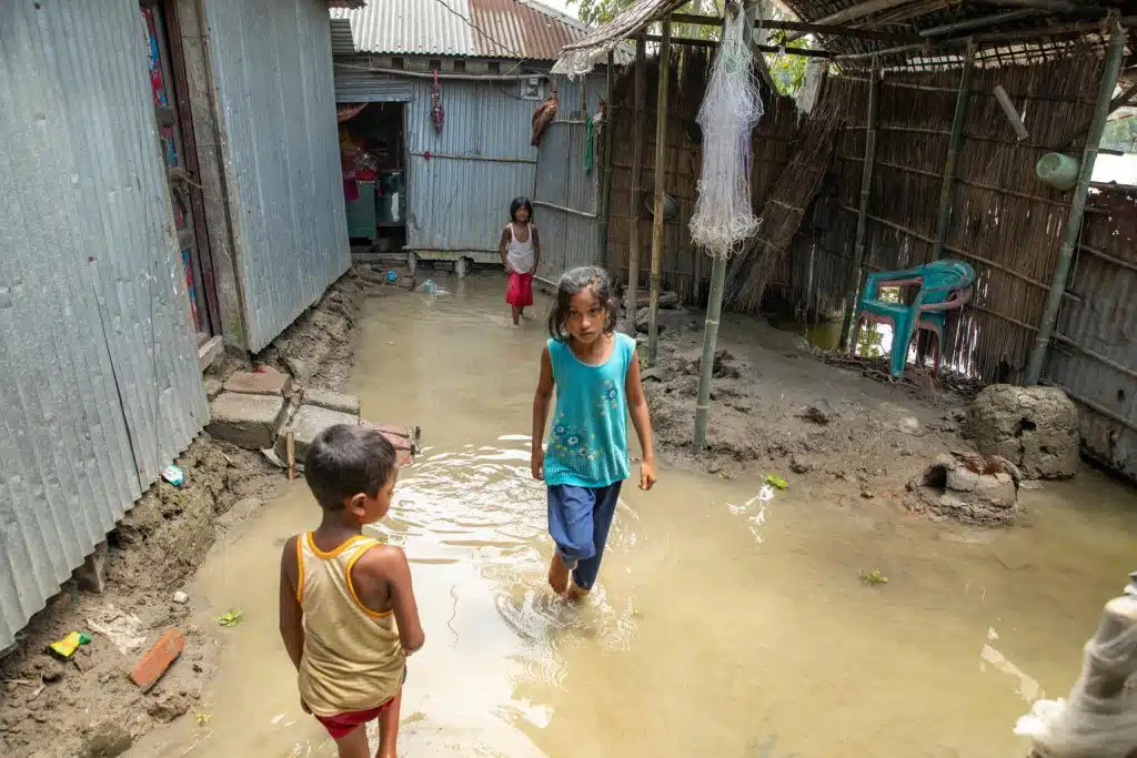 Le 9 juillet 2024 au Bangladesh, des enfants se frayent un chemin dans les eaux de la rivière Dharala, en crue depuis cinq jours. © UNICEF/UNI612995/Paulash