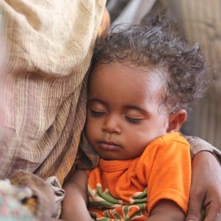 Un enfant dort sur les genoux de sa mère à Atbara. 25 juillet 2024. ©UNICEF/UNI418342/Mohamed