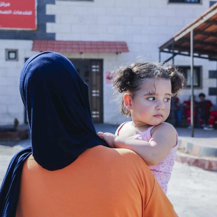 Naya, 18 mois, est dans les bras de sa mère, alors qu'elle se dirige vers la clinique soutenue par l'UNICEF au point de passage d'Al Arida, en Syrie.© UNICEF/UNI665007/Agha