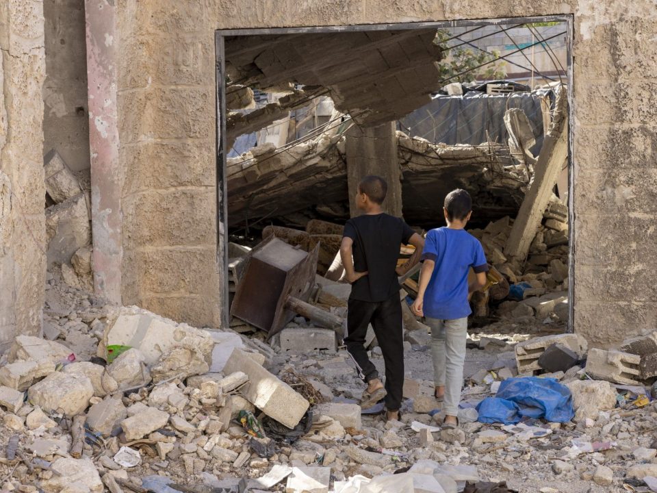 Des enfants du camp de réfugiés de Jénine en Cisjordanie regardent les abris détruits lors des récentes opérations militaires. © UNICEF/UNI671476/Izhiman