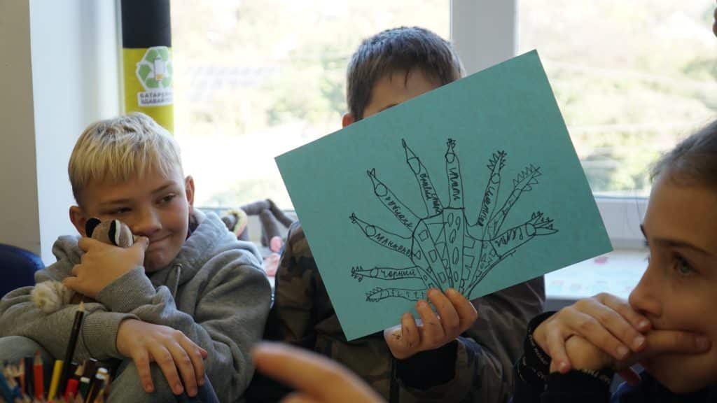 Un enfant montre son dessin, suite à une activité de groupe dans un Espace ami des enfants à Pidhorodnie (DNIPRO) en Ukraine. 24/10/2024 © UNICEF/Ihor Polianskyi