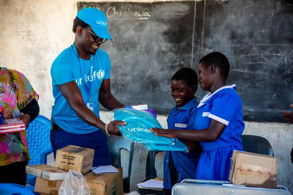 À Chauma, ville du sud de la Zambie, des élèves reçoivent des fournitures scolaires de la part d'un membre de l'équipe de l'UNICEF. © UNICEF/UNI581203/Mmina/Elephant Media