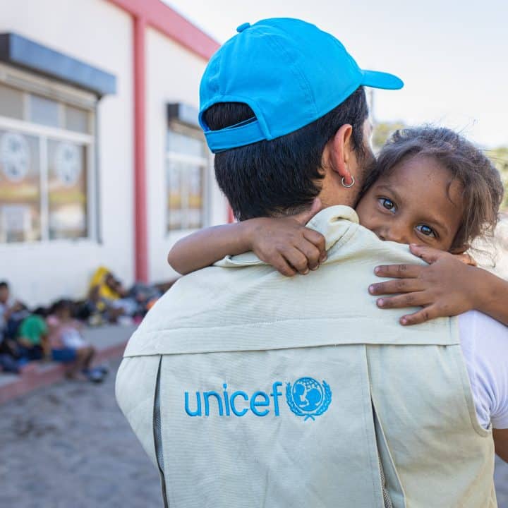 Le 26 février 2024, au Guatemala, Mario Gamarro, consultant en communication de l’UNICEF, prend Nicole, 8 ans, dans ses bras après avoir que la petite fille ait été examinée par une unité mobile de soin soutenue par l’UNICEF. © UNICEF/UNI694965/Willocq