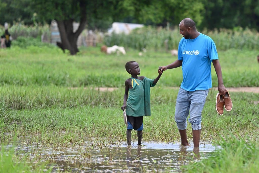 Un membre du staff de l'UNICEF et un enfant se frayent un chemin à Malow, en Ethiopie après que le village ait été inondé. © UNICEF/UNI594324/Dejongh